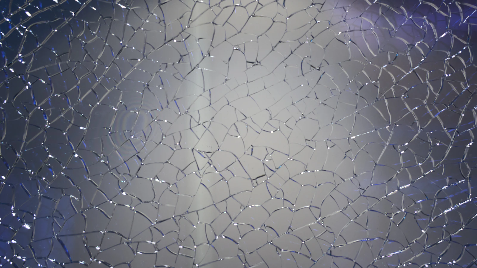 Close-up of cracked glass with blue light behind it