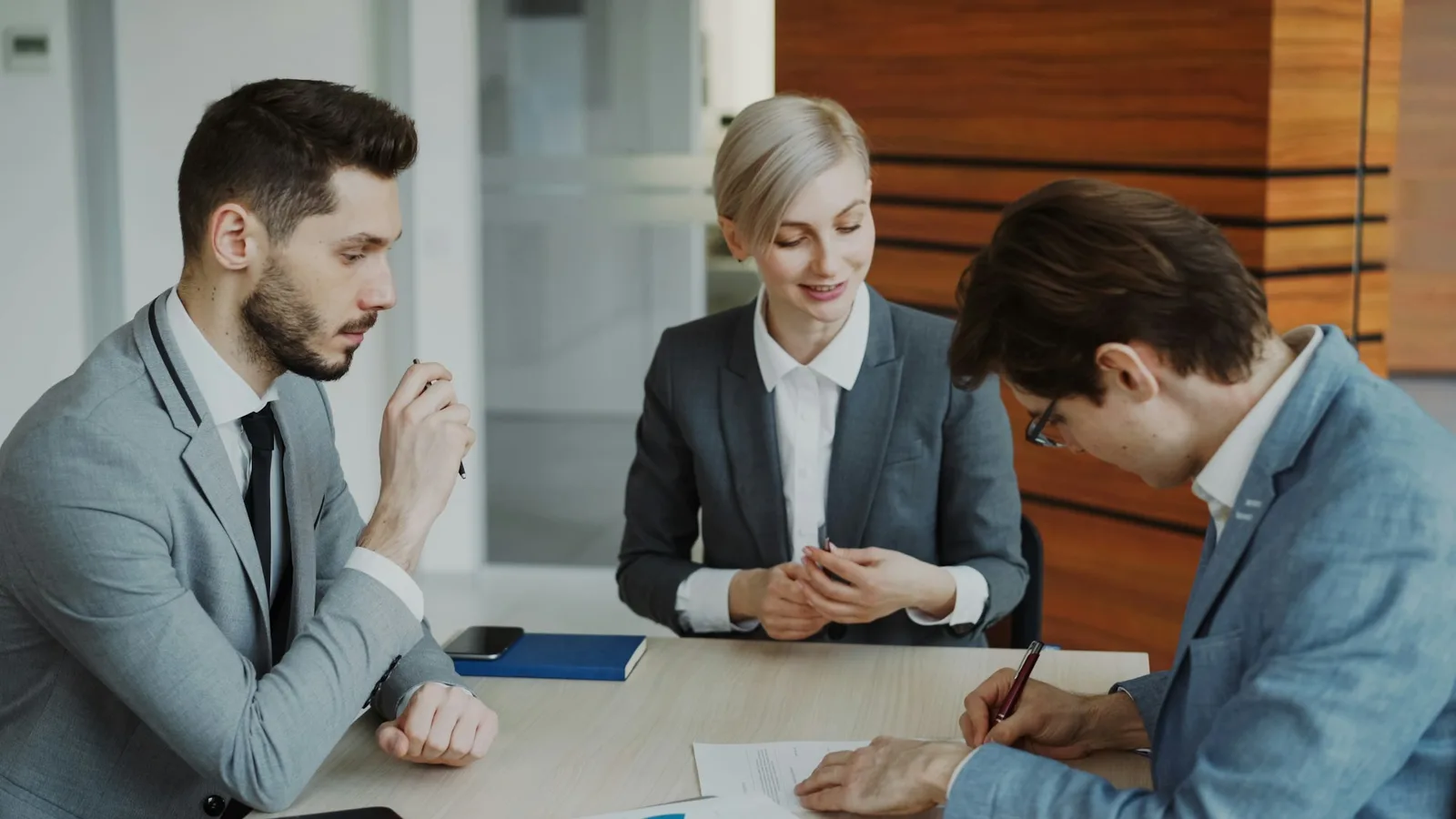 Three people reviewing and signing paperwork at a table