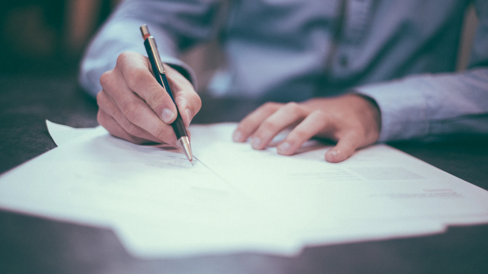 A person writing on a document at a desk