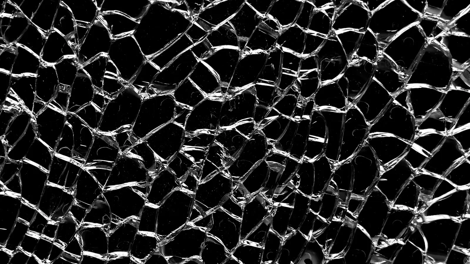 Close-up pattern of fractured glass against a dark background