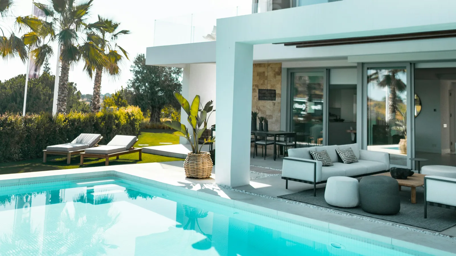 Glass patio doors and outdoor seating beside a swimming pool
