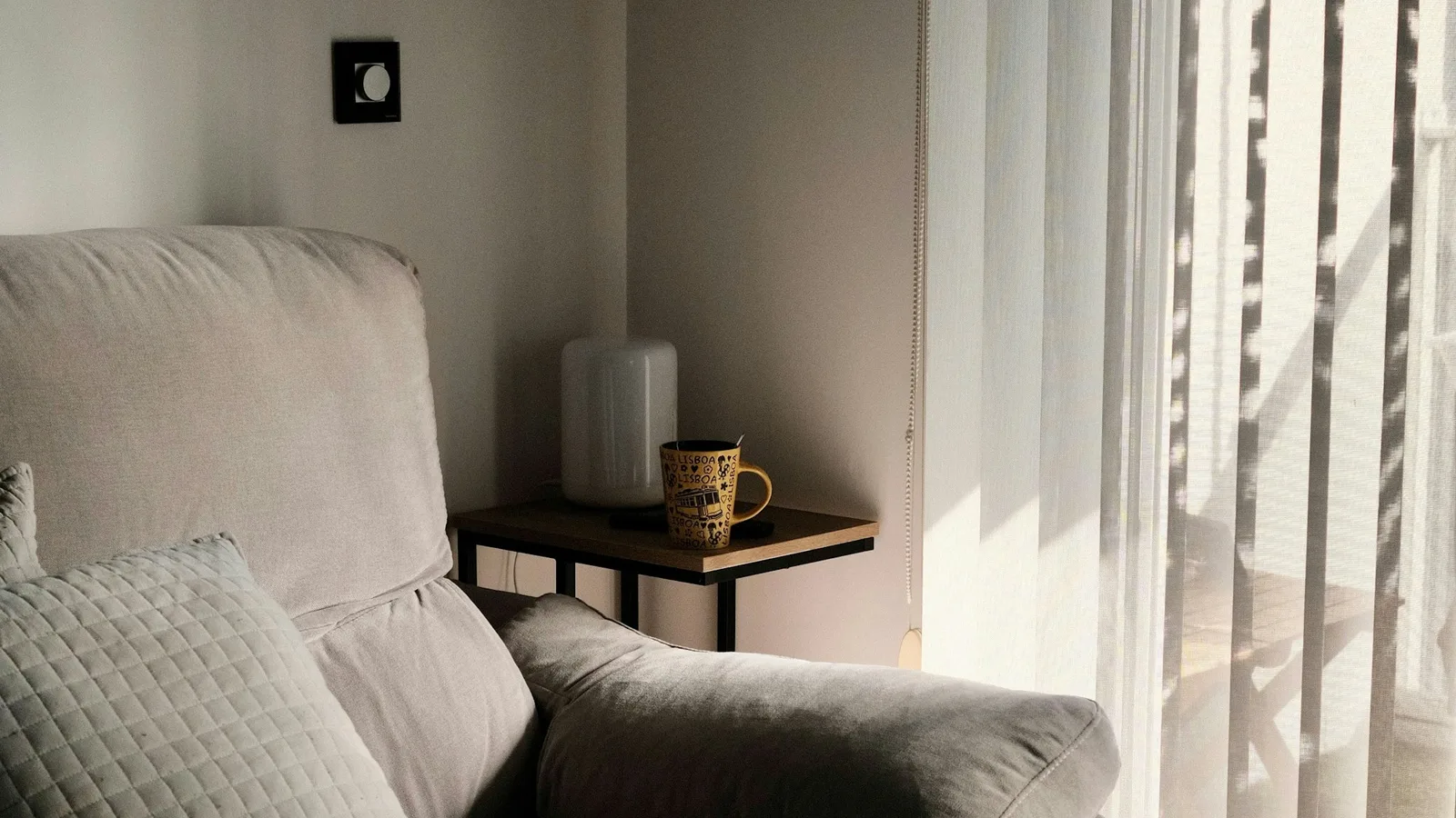Sunlight falling across an upholstered chair beside window blinds