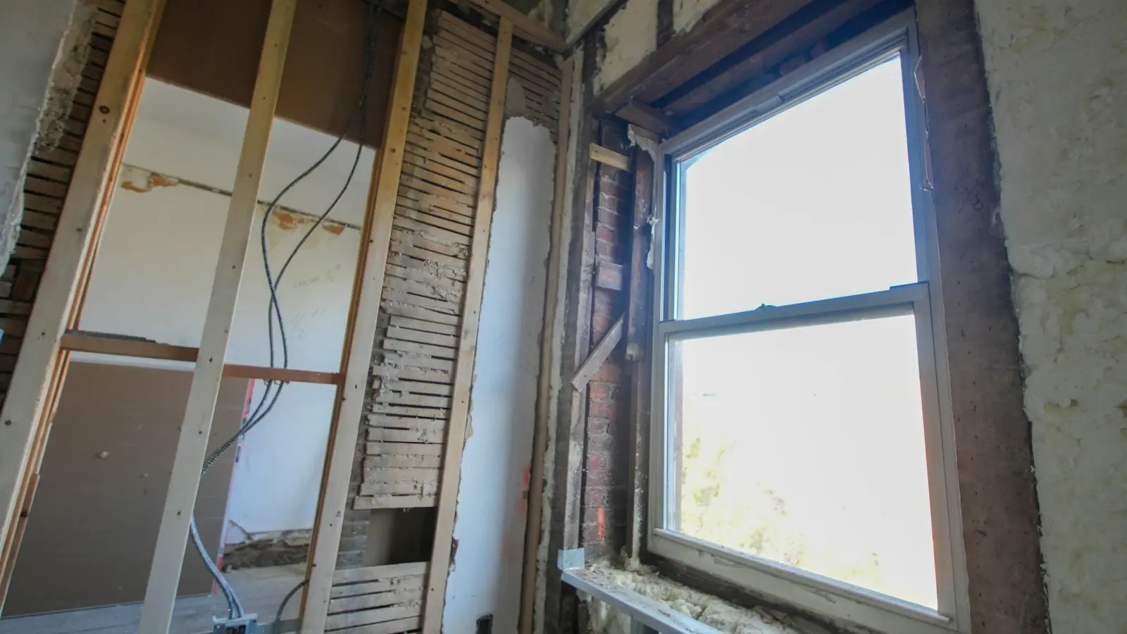 Exposed wall framing and masonry surrounding a window opening during renovation