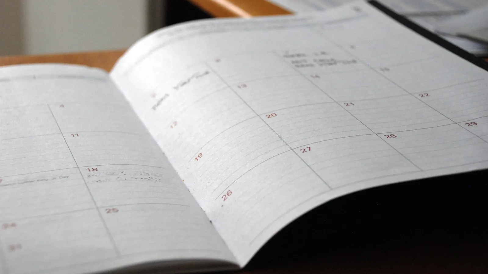 An open monthly planner on a wooden desk